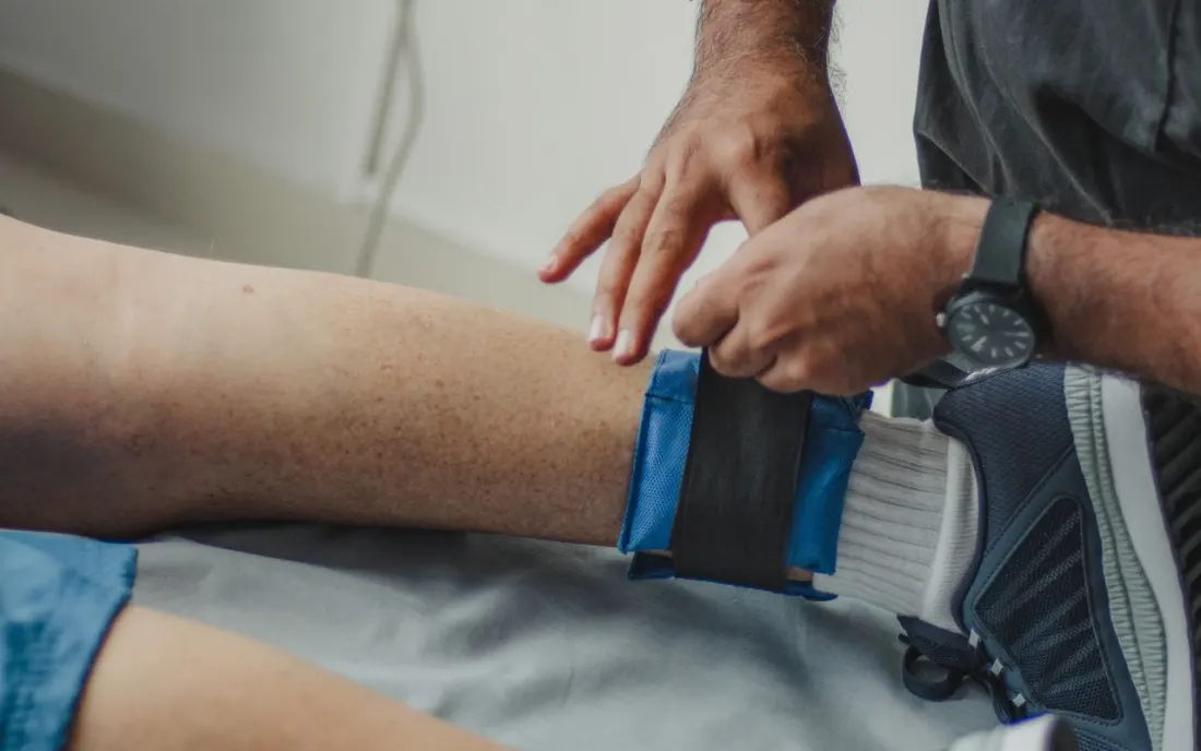 Therapist's hands guiding a patient's leg during treatment